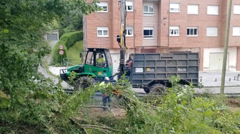 Imagen Operario y autocargador retirando restos vegetales del cauce